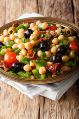 Healthy food: salad balela with chickpeas, tomatoes, onions, olives and herbs close-up. vertical