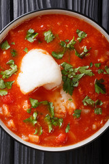Cod fish tomato soup with celery and parsley close-up in a bowl. Vertical top view