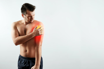 Front view, the man holds his hands to the forearm, pain in his hand, pain in the shoulder highlighted in red. Light background. The concept of medicine, massage, physiotherapy, health.
