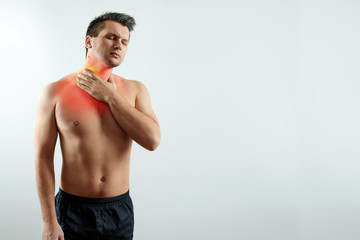 Front view, a man holds his hands behind his throat, a sore throat highlighted in red, sore throat, flu. Light background. The concept of medicine, massage, physiotherapy, health.