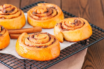 Classic cinnamon rolls - cinnabons won a wire rack. Wooden background.