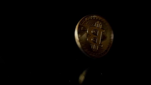 rotating, twisting, swirling, spinning cryptocurrency coin, bitcoin on black, slow motion