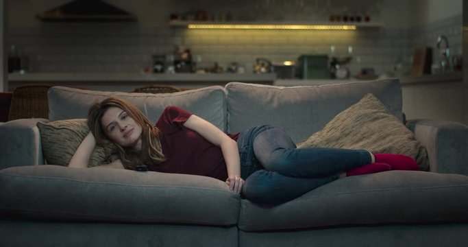 Woman lying comfortably on a sofa watching tv.