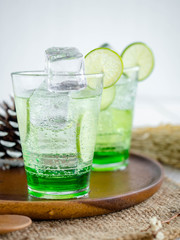 Green Lemon soda in glass on wood tray and white table