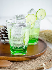 Green Lemon soda in glass on wood tray and white table