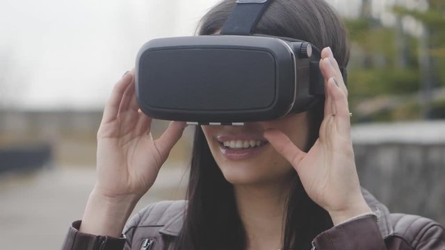 young woman getting experience in using VR-headset or virtual reality headset outdoor