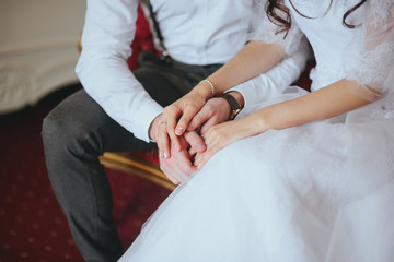 Bride and groom on a luxury hotel, kissing on a sofa. hands of large platoons