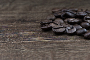 Coffee beans on a dark background and a wooden table. Closeup.