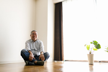 部屋の床に座っているシニア男性