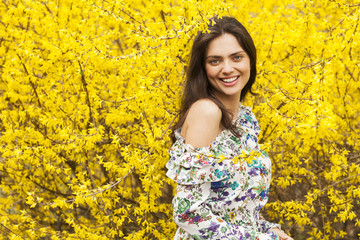 Young woman in the flowered, yellow garden in the spring time