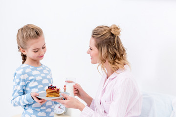 daughter giving mother pancakes on happy mothers day