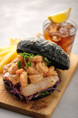 Black burger with fish and shrimps. Fishburger with prawns