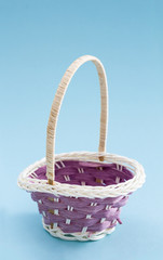 Small decorative empty wicker basket, on light blue background.