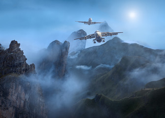 Fototapeta na wymiar Passenger planes flying low above mountains at night