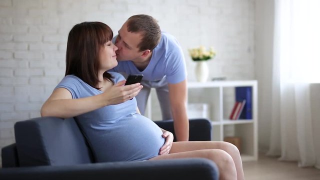 pregnant woman with smartphone and her husband at home