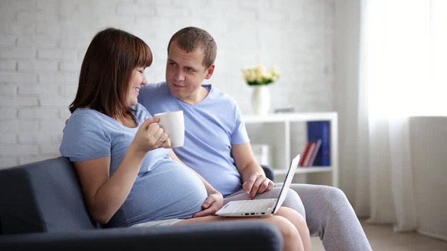 online shopping concept - pregnant woman and her husband with laptop at home
