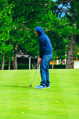 Man is playing golf on a green grass court.
