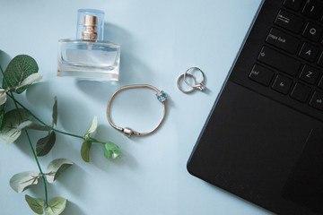 Laptop with eucalyptus, rings. perfume, on light blue background. Top view, flat lay. Blog and blogging background.