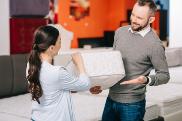 couple choosing folding mattress together in furniture store with arranged mattresses