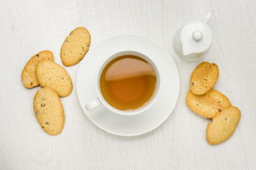 cup of tea on white table with cookies and milk jug
