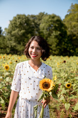 Girl  in the sunflowers field enoying the sun picking up flower dancing laughing spinning and talking with big smile / red lip stick