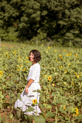 Girl  in the sunflowers field enoying the sun picking up flower dancing laughing spinning and talking with big smile / red lip stick