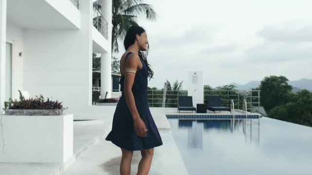 Asian Woman Gesturing Follow Me And Walking Along Infinity Pool On Luxury Villa