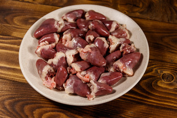 Raw chicken hearts on wooden table
