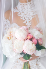 close-up of the bride in a beautiful dress that holds a wedding bouquet and is covered with veil
