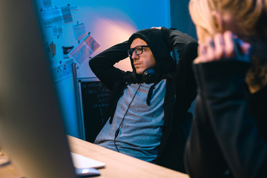 female hacker looking at depressed accomplice at workplace