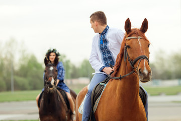 Obraz premium The guy rides on a horse and looks at his girlfriend who rides a horse behind him
