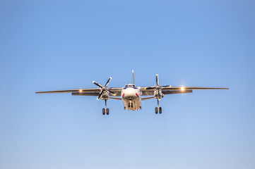 white airplane with screw engines with chassis released in the blue sky, front view