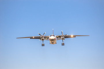 white airplane with screw engines with chassis released in the blue sky, front view