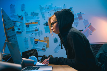 Obraz na płótnie Canvas side view of female hacker developing malware in dark room