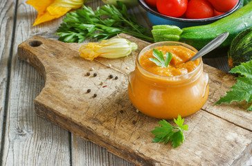 Squash zucchini paste in a glass jar surrounded by the ingredients