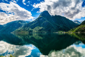 Fototapeta na wymiar Norway landscapes. The mountains are reflecting in the water of the fjord on a sunny day