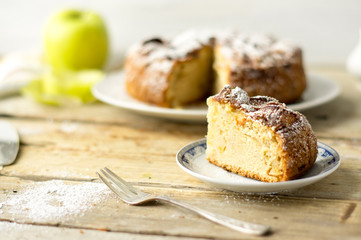 2. Piece of a freshly baked homemade apple pie with cake, fresh apple, silver fork and a powdered sugar on a side