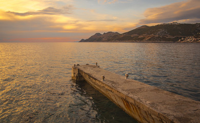 Sunset with cloud sky, background mountains and sea dock