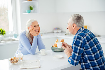 Portrait of charming attractive sweet cute lovely woman sitting in front of her lover at the table in kitchen, having mug with tea looking to each other, spending nice time together