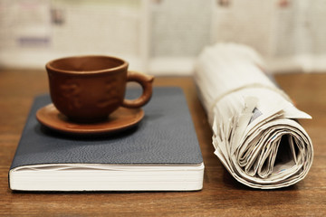 English breakfast with newspapers. Daily papers with fresh news, notebook and cup of tea (coffee) on wooden table. Reading journals in the morning