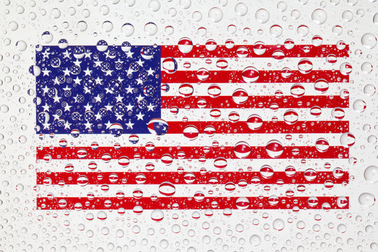 American flag behind a glass covered with rain drops.