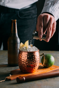 Man's hand pouring vodka in cocktail mug