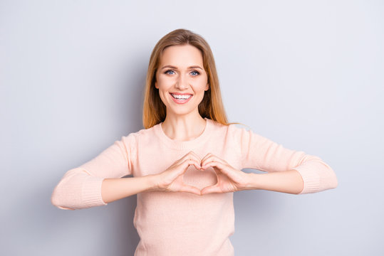 Close up portrait of charming lovely sweet sincere cute adorable pretty with toothy beaming smile woman making demonstrating heart on chest wearing casual light sweater isolated on gray background