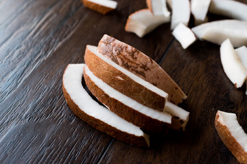 Slice of Fresh Coconut Pieces on Dark Wooden Surface.