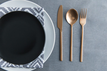 top view of black empty plate, napkin and old fashioned tarnished cutlery on tabletop - obrazy, fototapety, plakaty