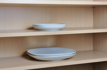 Different white dishes in cupboard in the kitchen. Scandinavian style.