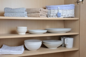Different white dishes in cupboard in the kitchen. Scandinavian style.