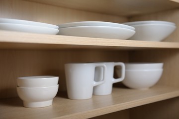 Fototapeta na wymiar Different white dishes in cupboard in the kitchen. Scandinavian style.