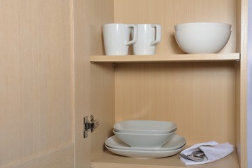 Different white dishes in cupboard in the kitchen. Scandinavian style.