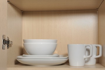 Different white dishes in cupboard in the kitchen. Scandinavian style.